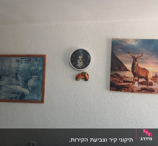 קיר פנימי בגימור טקסטורה דקורטיבית מחוספסת ועליו תמונות ושעון קיר